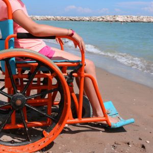 little girl on the special orange wheelchair on the beach