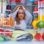 woman holding her hair in frustration as she looks in her fridge