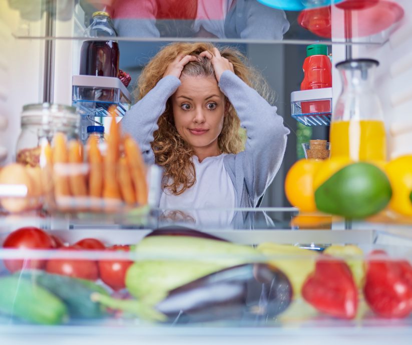 woman holding her hair in frustration as she looks in her fridge