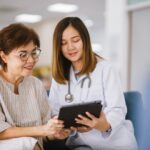 older woman and doctor looking at tablet in hospital