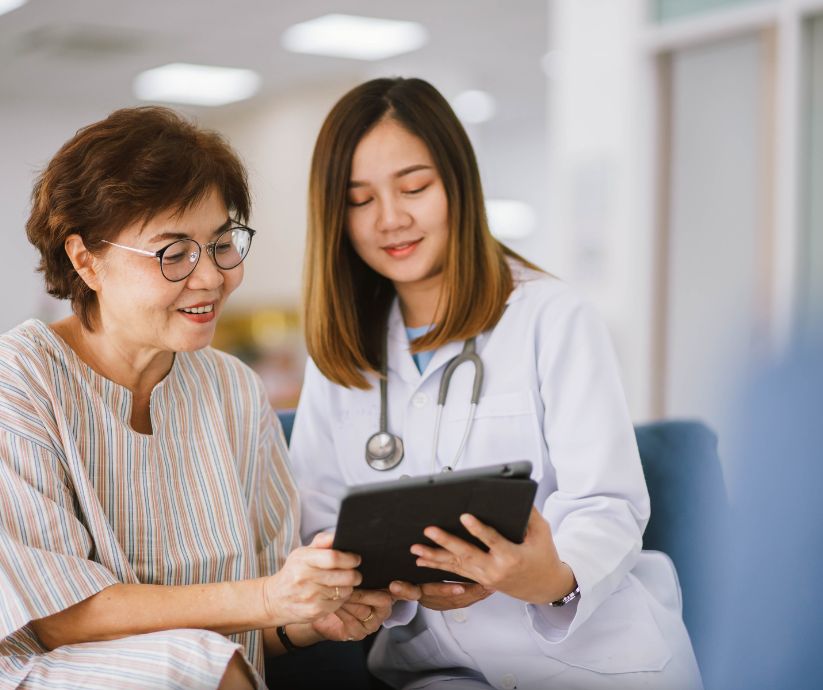 older woman and doctor looking at tablet in hospital