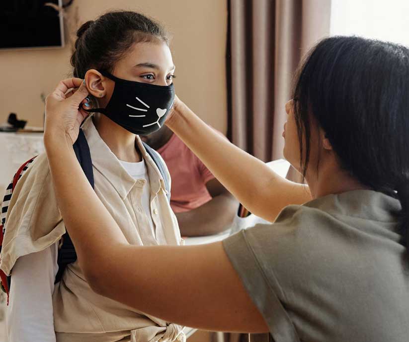 mom putting mask on a pre-teen girl